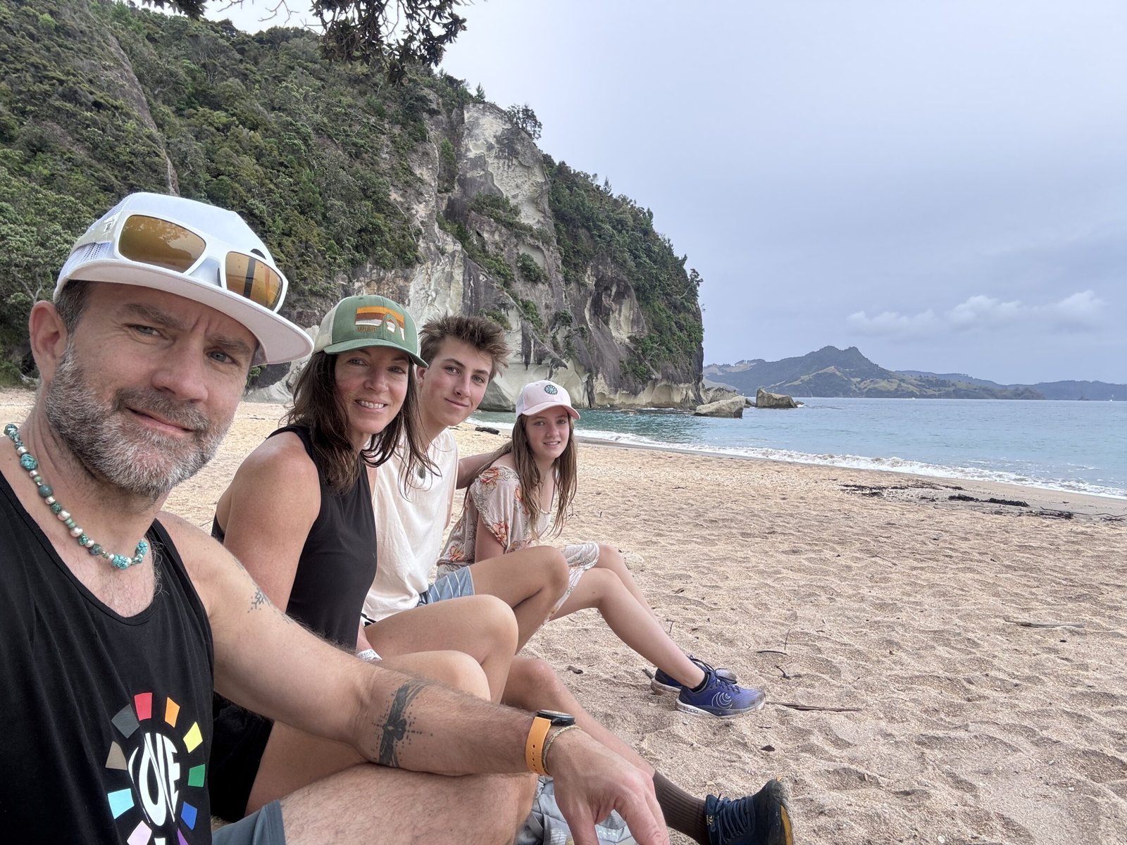 Jayson Gaddis with his family sitting down on the beach near a cliff
