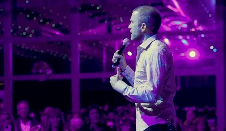 Jayson Gaddis speaking in a purple-lighted room